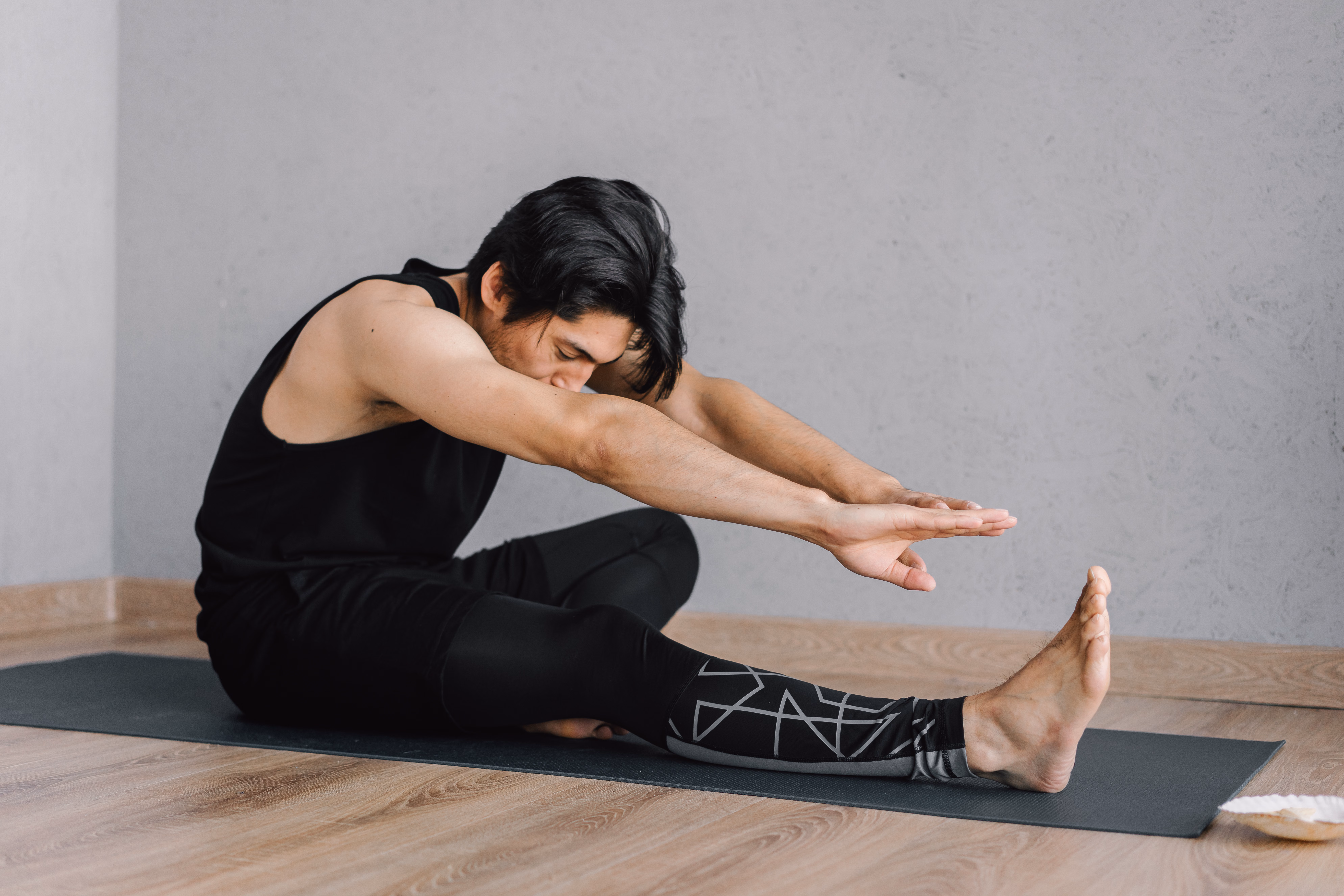 A person stretching on a mat by a window while wearing comfortable clothes